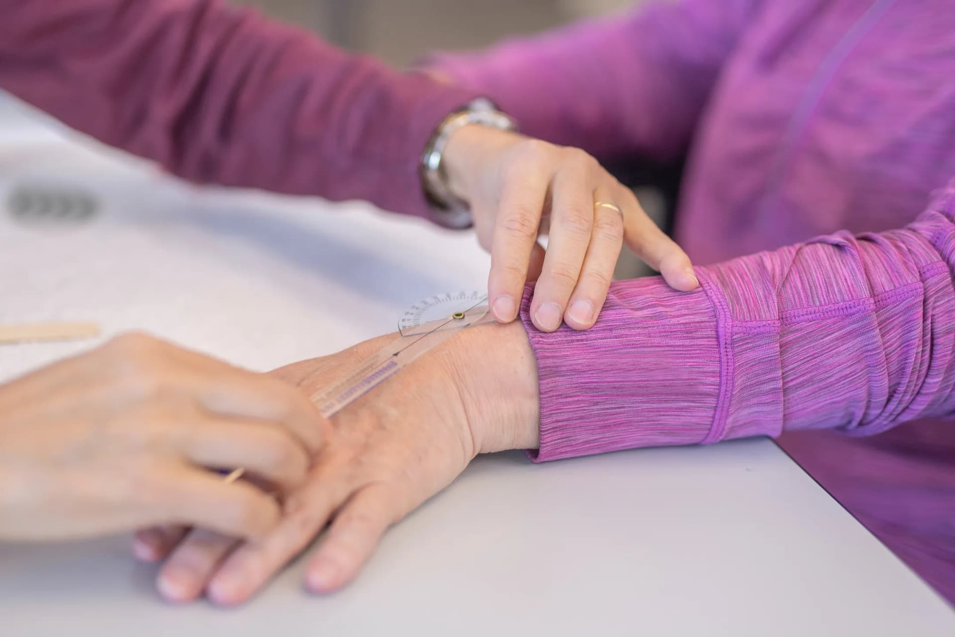 Ergotherapeutin misst den Bewegungsumfang der Hand einer Seniorin